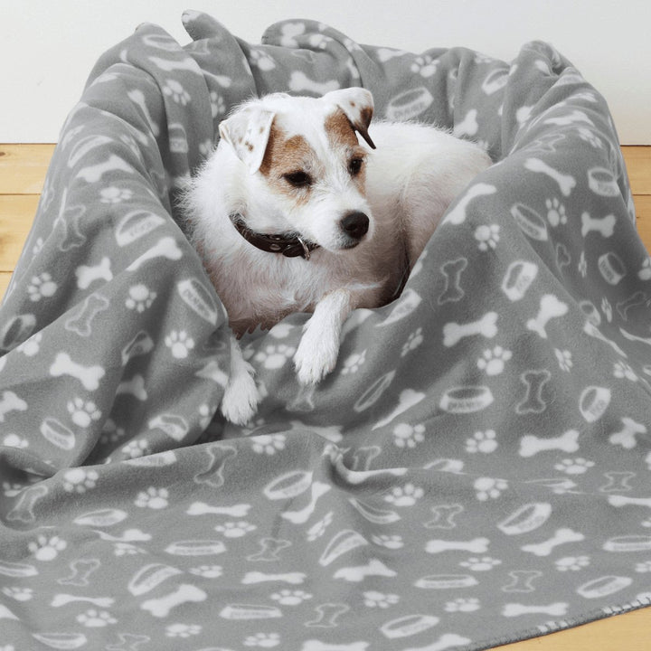 Dog laying down in pet bed with dark grey printed blanket