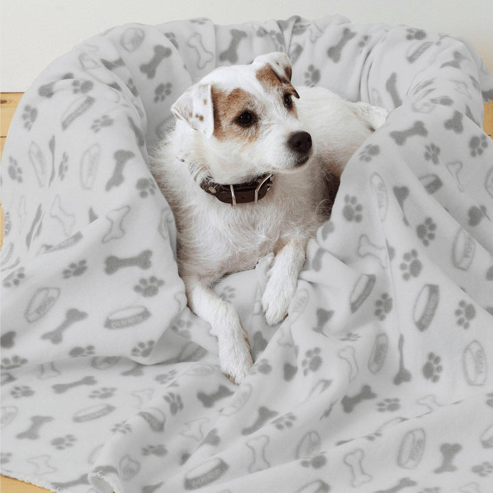 Dog laying down in pet bed with grey printed blanket